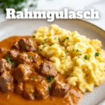 Leckeres Rahmgulasch serviert in einer Schüssel auf einem Holztisch.