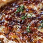 Ein köstliches Stück Zwiebelkuchen auf einem Teller, garniert mit frischen Kräutern.