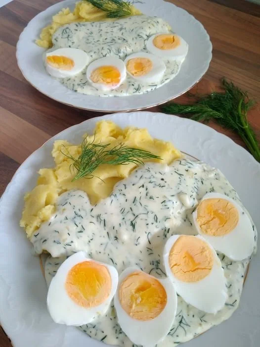 Eier in Dillsoße mit Kartoffeln auf einem Teller serviert