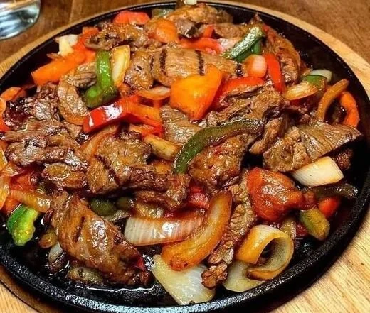 Leckere Rindfleisch Fajitas mit frischem Gemüse und Gewürzen serviert.