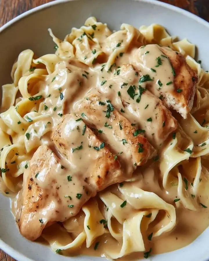 Buttered Nudeln mit Hähnchen und Pilzen auf einem Teller serviert.