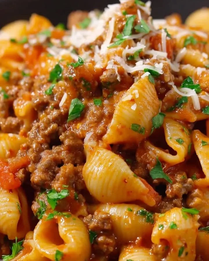 Ein Teller mit One Pot Käse Taco Pasta, garniert mit Käse und frischen Kräutern.