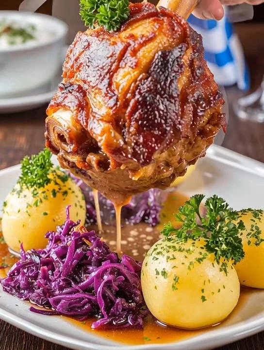 Schweinehaxe serviert mit Knödeln und Sauerkraut auf einem Teller