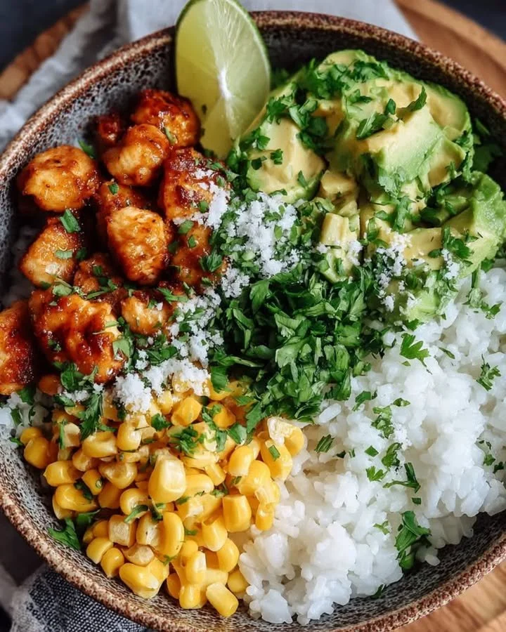 Street Corn Chicken Rice Bowl mit Avocado und Limettendressing auf einem Teller
